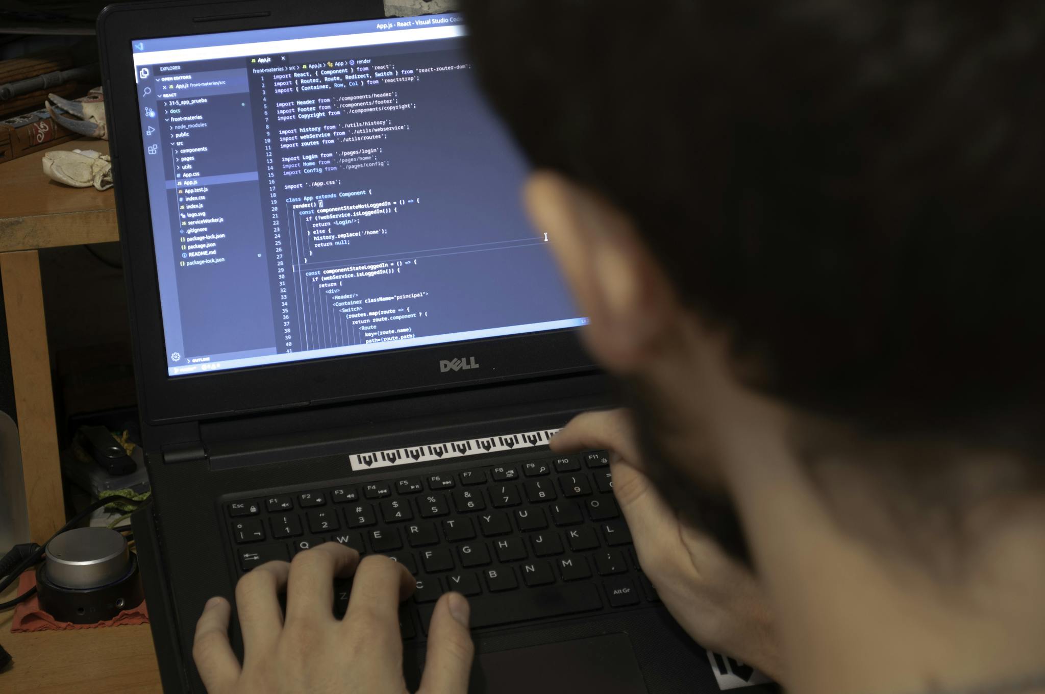 Close-up view of a programmer typing code on a laptop in a workspace.